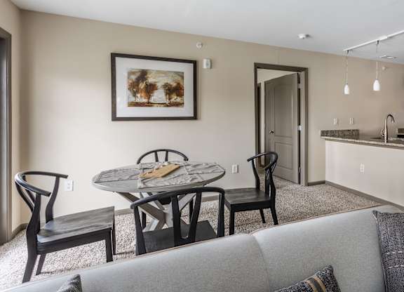 A modern living room with a grey couch and a dining table with chairs.