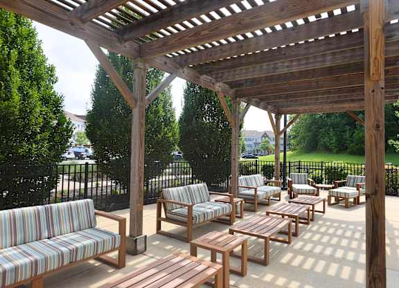 A wooden pergola with striped couches and tables.