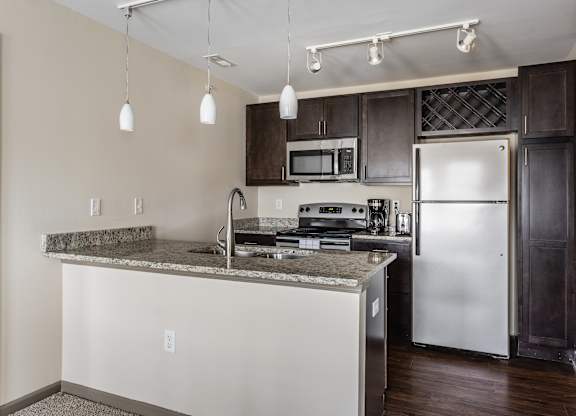 A kitchen with a granite countertop and stainless steel appliances.