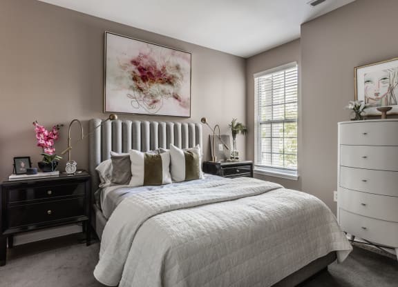 a bedroom with a bed and a dresser at Alexandria of Carmel Apartments, Carmel, Indiana