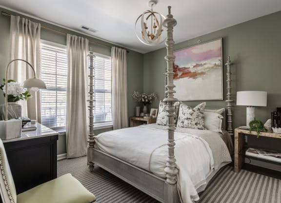 a bedroom with a white bed and a painting on the wall at Alexandria of Carmel Apartments, Carmel, IN, 46032