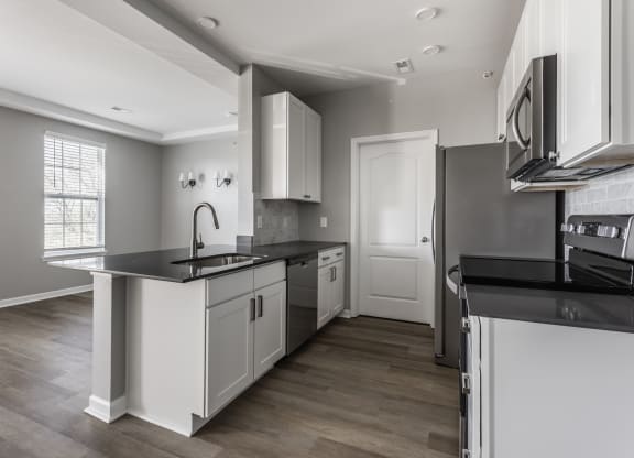 an empty kitchen with white cabinets and black counter tops  at Alexandria of Carmel Apartments, Carmel, IN, 46032