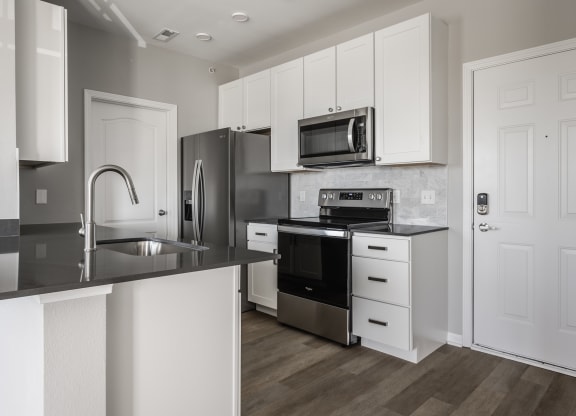 a kitchen with white cabinets and stainless steel appliances at Alexandria of Carmel Apartments, Indiana