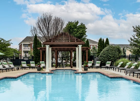 a swimming pool with a gazebo and chairs around it at Alexandria of Carmel Apartments, Indiana