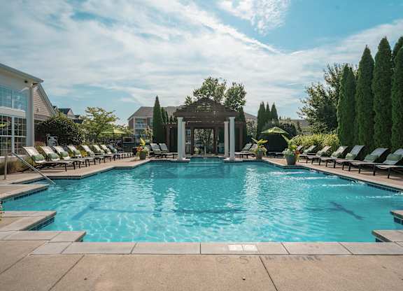 A large outdoor swimming pool surrounded by lounge chairs and trees at Alexandria of Carmel Apartments, Carmel, Indiana