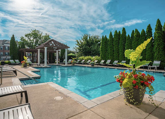 A pool area with a gazebo and lounge chairs at Alexandria of Carmel Apartments, Carmel, Indiana