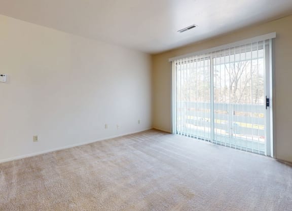 an empty living room with a sliding glass door at Apple Ridge Apartments, Walker, Michigan