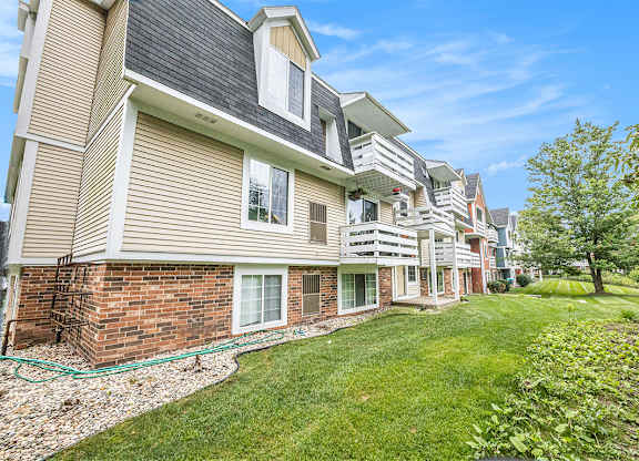 An exterior apartment building with lush green lawn and shade trees at Apple Ridge Apartments, Michigan, 49534