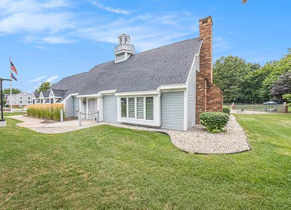 A leasing office with a brick chimney surrounded by a grassy lawn at Apple Ridge Apartments, Michigan, 49534