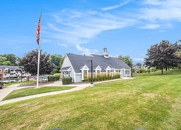 A leasing office with a flag on a pole in front of a green lawn at Apple Ridge Apartments, Michigan, 49534