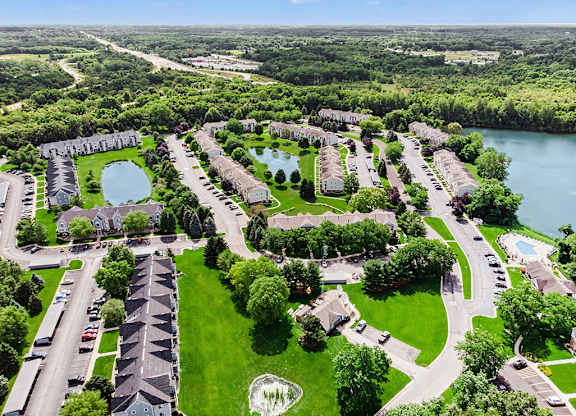 A bird's eye view of a residential area with apartment buildings, roads, and a pond at Arbor Lakes Apartments in Elkhart, IN