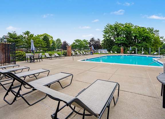 A pool surrounded by lounge chairs and umbrellas at Arbor Lakes Apartments in Elkhart, IN
