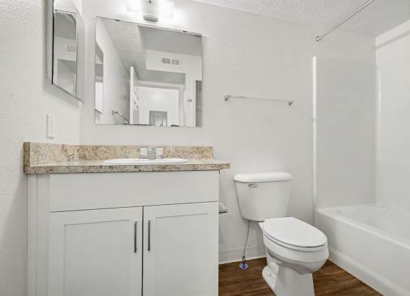 A white bathroom with a mirror, toilet and bathtub at Autumn Lakes Apartments and Townhomes, Mishawaka, 46544