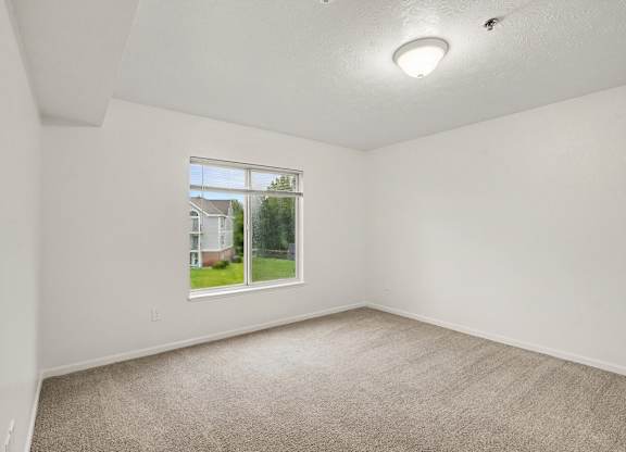 A bedroom with a carpeted floor and a window with a view at Autumn Lakes Apartments and Townhomes, Mishawaka, 46544