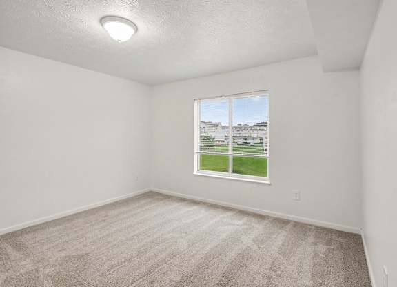 A spacious bedroom with a carpeted floor and a window at Autumn Lakes Apartments and Townhomes, Mishawaka, 46544