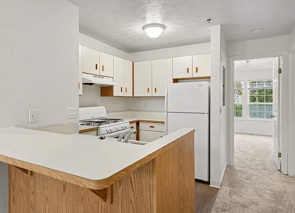 A kitchen with white appliances and wooden cabinets at Autumn Lakes Apartments and Townhomes, Mishawaka, 46544