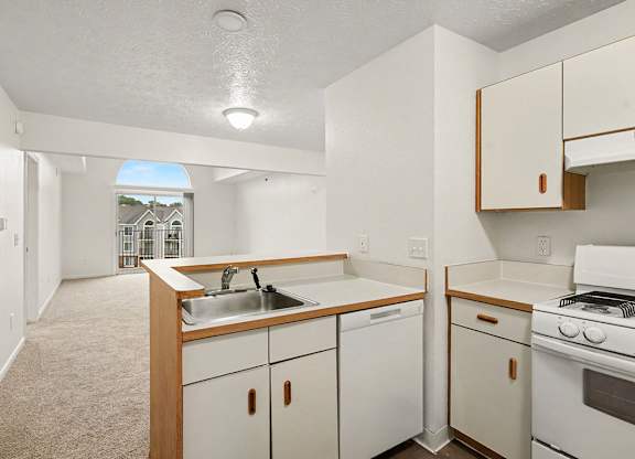 A kitchen with white appliances and a breakfast bar at Autumn Lakes Apartments and Townhomes, Mishawaka, 46544