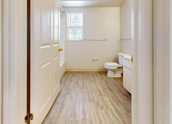 A white bathroom with a toilet, sink, and window at Autumn Lakes Apartments and Townhomes in Mishawaka, IN