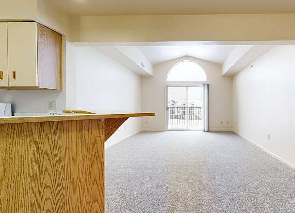 A living room with a carpeted floor and cathedral ceiling at Autumn Lakes Apartments and Townhomes in Mishawaka, IN