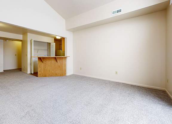 A living and dining room with a carpeted floor and a cathedral ceiling at Autumn Lakes Apartments and Townhomes in Mishawaka, IN