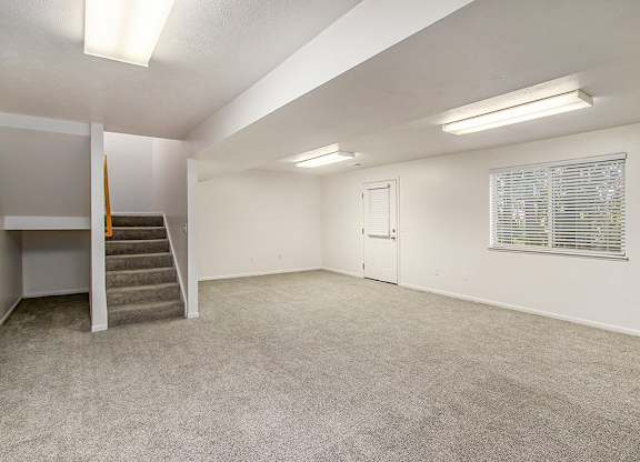 A spacious room with a staircase and a window with blinds at Autumn Lakes Apartments and Townhomes, Mishawaka, 46544