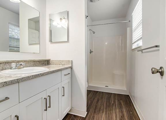 A bathroom with a sink, mirror, and wooden floor at Autumn Lakes Apartments and Townhomes, Mishawaka, 46544