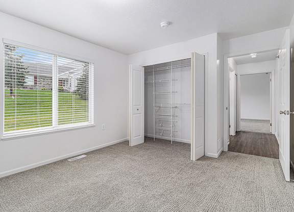 A bedroom with a walk-in closet and a window with blinds at Autumn Lakes Apartments and Townhomes, Mishawaka, 46544