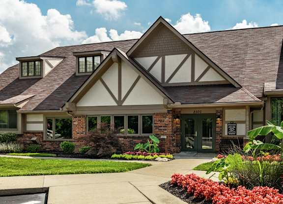 A house with a brown roof and white walls with a green lawn in front