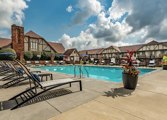 A pool area with sun loungers and a building in the background
