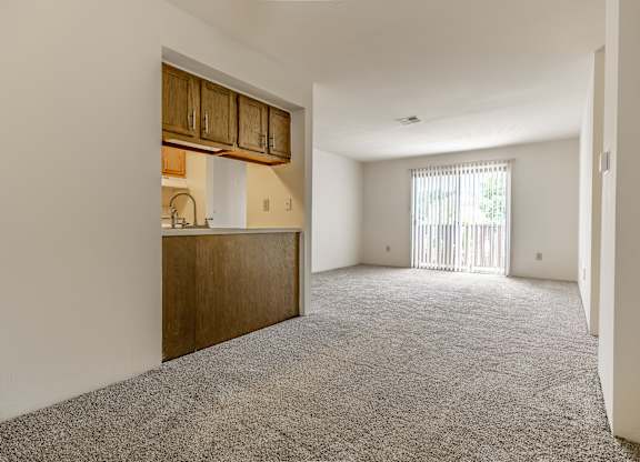 A room with a grey carpet and wooden cabinets