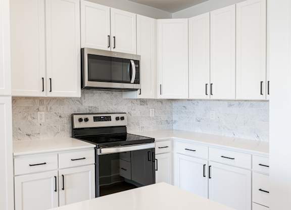a kitchen with white cabinets and a black stove and microwave at Avant & Avant II, Carmel, IN, 46032