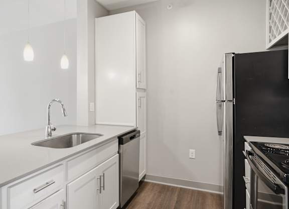A modern kitchen with white cabinets and a black refrigerator.