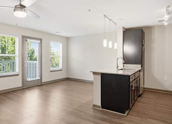 A kitchen area with a black fridge and a ceiling fan.