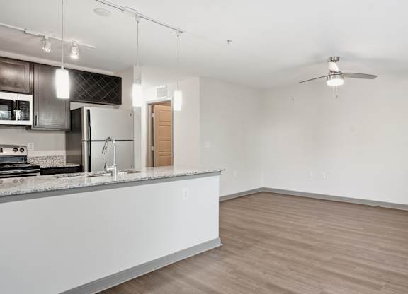 A kitchen with a counter and a fan on the ceiling.