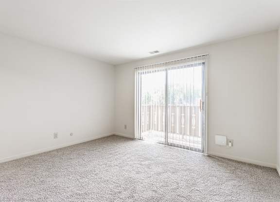 A room with a carpeted floor and a sliding glass door