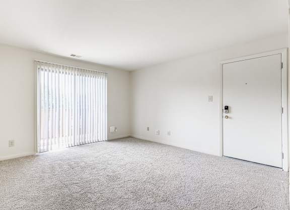 A room with a carpeted floor and a sliding glass door