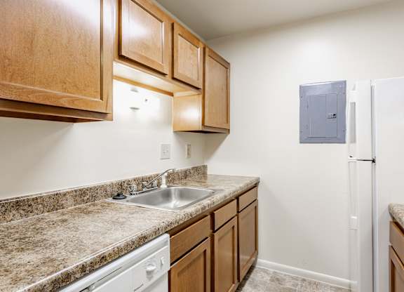 A kitchen with a white fridge and brown cabinets