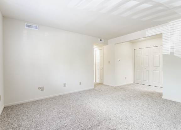 A spacious room with white walls and carpeted floor