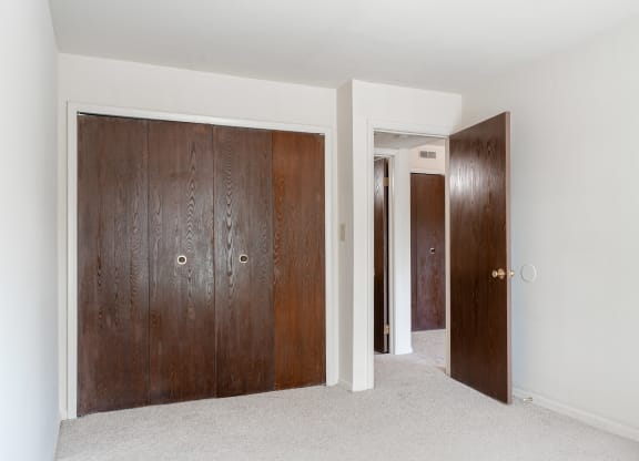 a room with two wooden doors and a carpeted floor at Bavarian Village Apartments, Indianapolis, IN