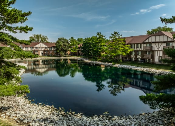 a large pond in front of a building with trees