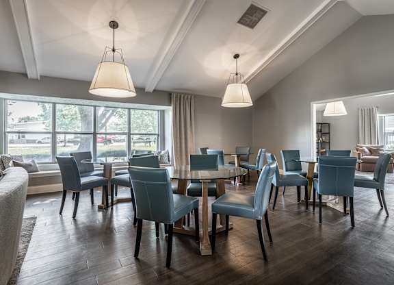 A room with a table and chairs with a window in the background.