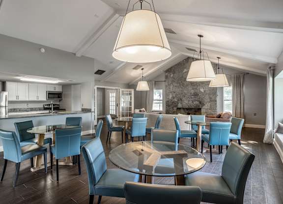 A modern dining room with a glass table surrounded by blue chairs.