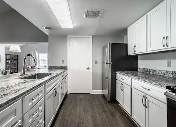 A modern kitchen with white cabinets and a black refrigerator.