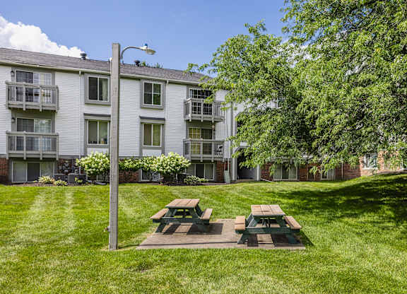 A grassy area with a picnic table in front of a building.