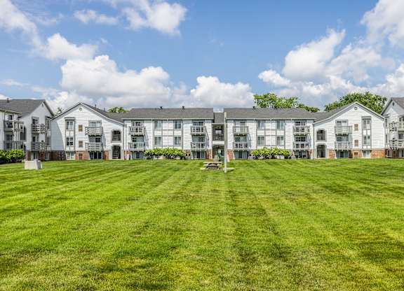 A row of white apartment buildings with green lawns in front.