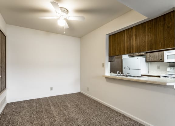 an empty room with a kitchen and a ceiling fan at Bay Pointe Apartments in IN 47909