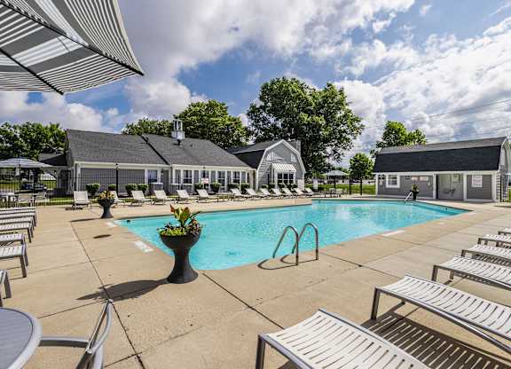 A pool area with sun loungers and a building in the background.