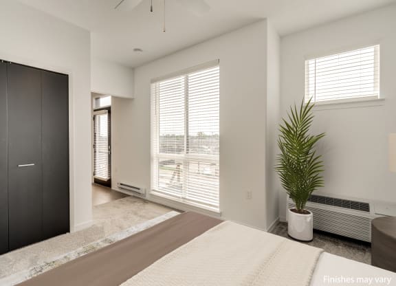 a bedroom with a large window and a large potted plant  at Uptown Square Apartments, Michigan, 48083