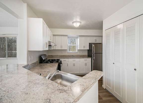 A kitchen with white cabinets and a breakfast bar at Black Sand Apartment Homes in Lincoln, NE