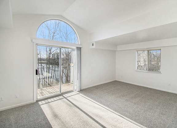 A living room with a cathedral ceiling, large arched window and a carpeted floor at Black Sand Apartment Homes in Lincoln, NE
